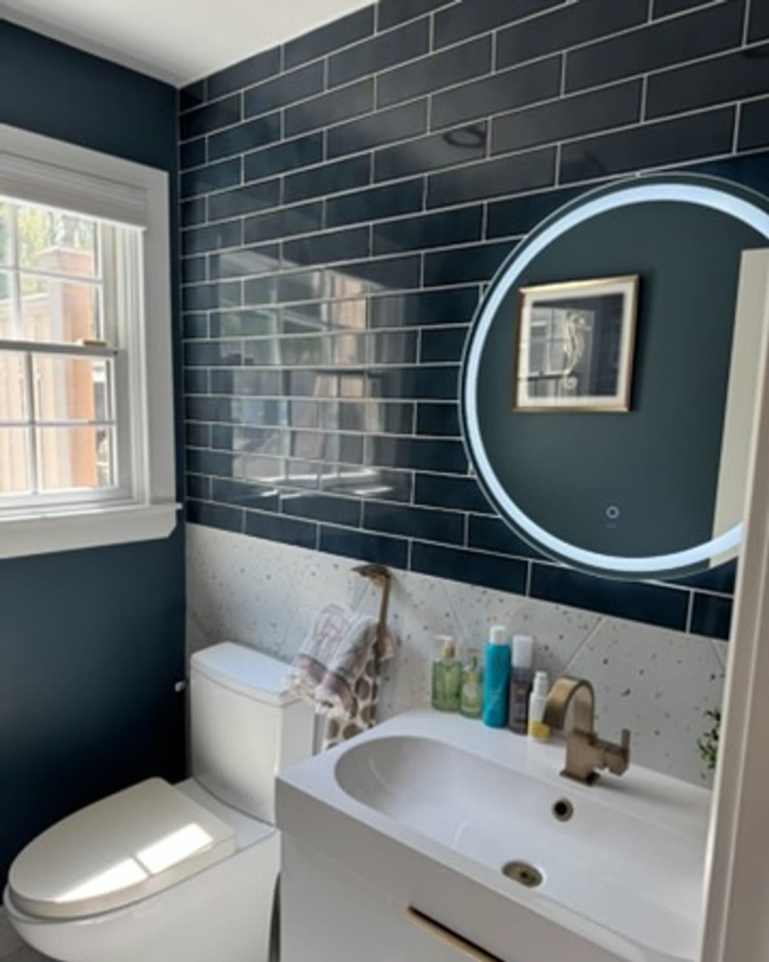 Navy subway-tile bathroom with backlit round mirror
